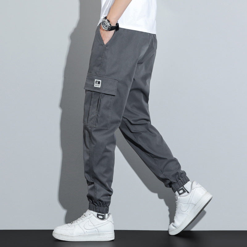 Person wearing gray cargo pants and white sneakers on a plain background