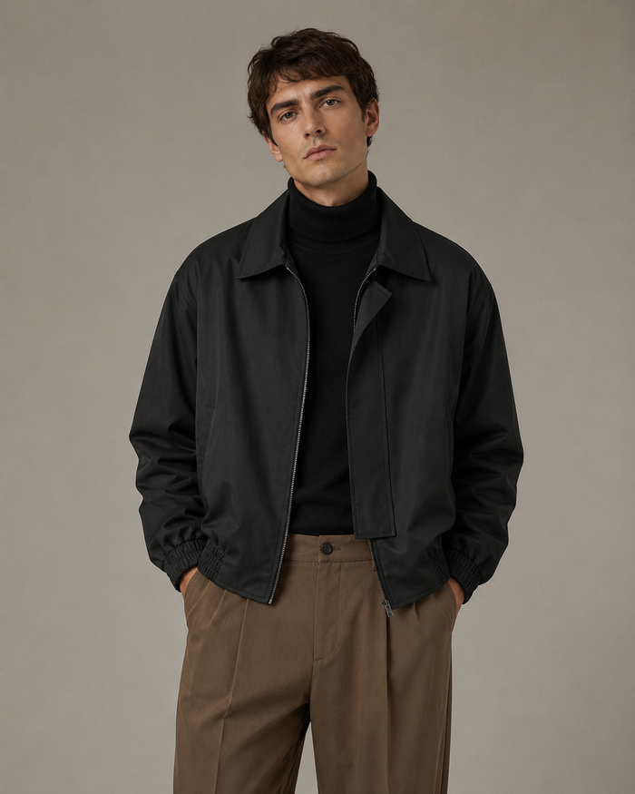 Male model wearing a black lapel zip jacket with dark brown trousers in a professional studio