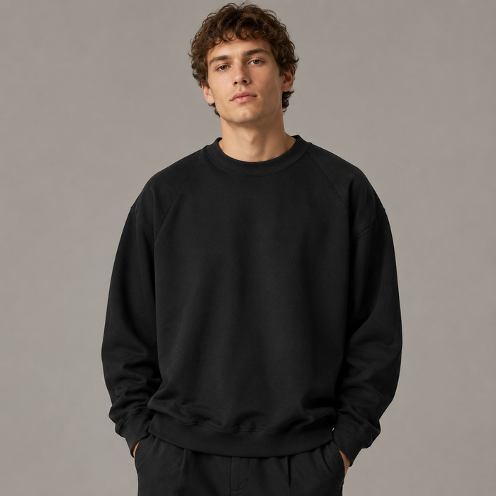 European male model wearing a black oversized crewneck sweatshirt in a professional studio