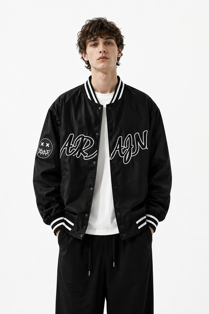 Male model wearing a black varsity jacket in a professional studio