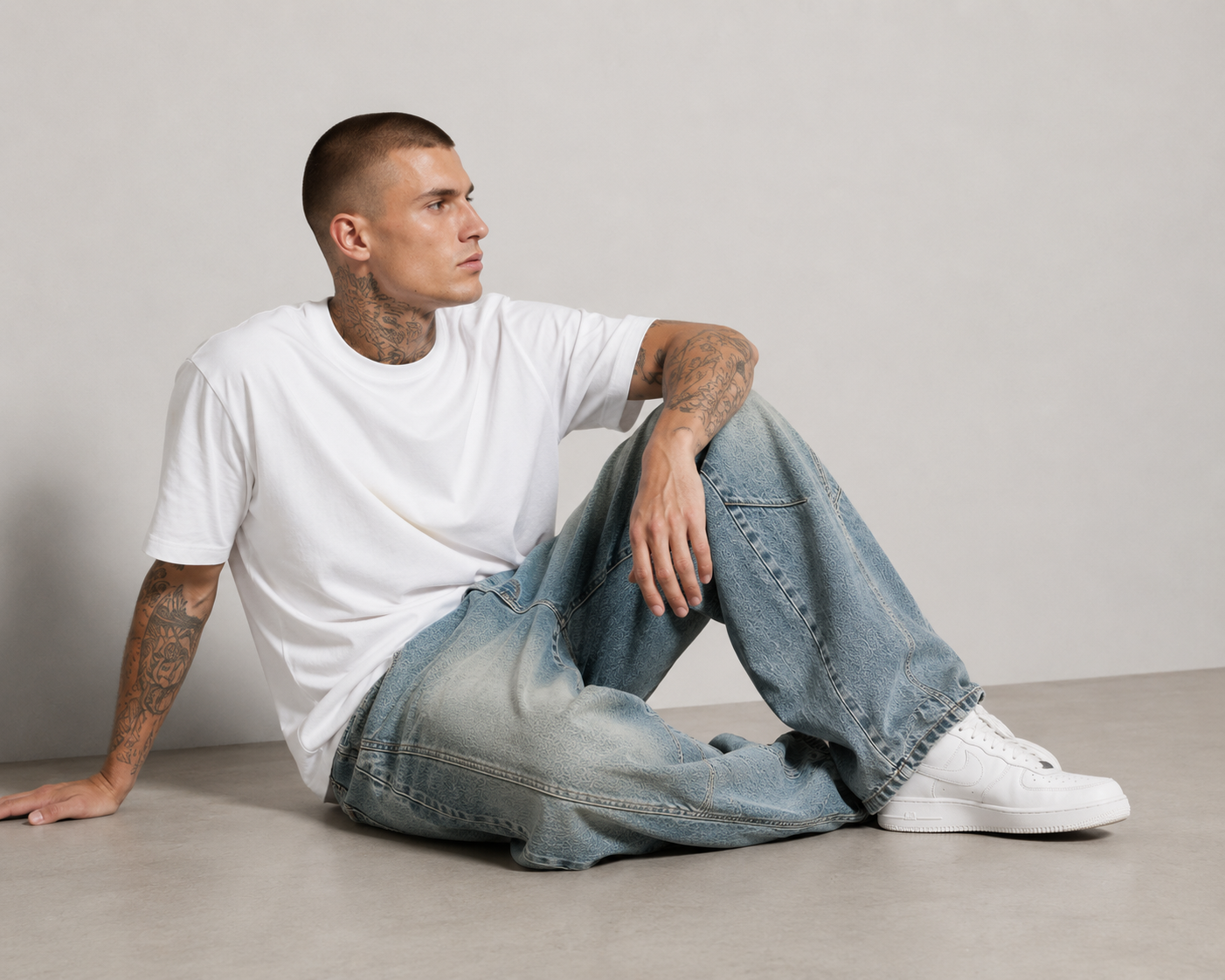 Nikolai Volkov wearing light-wash loose straight-leg utility jeans in a seated side pose in a professional studio