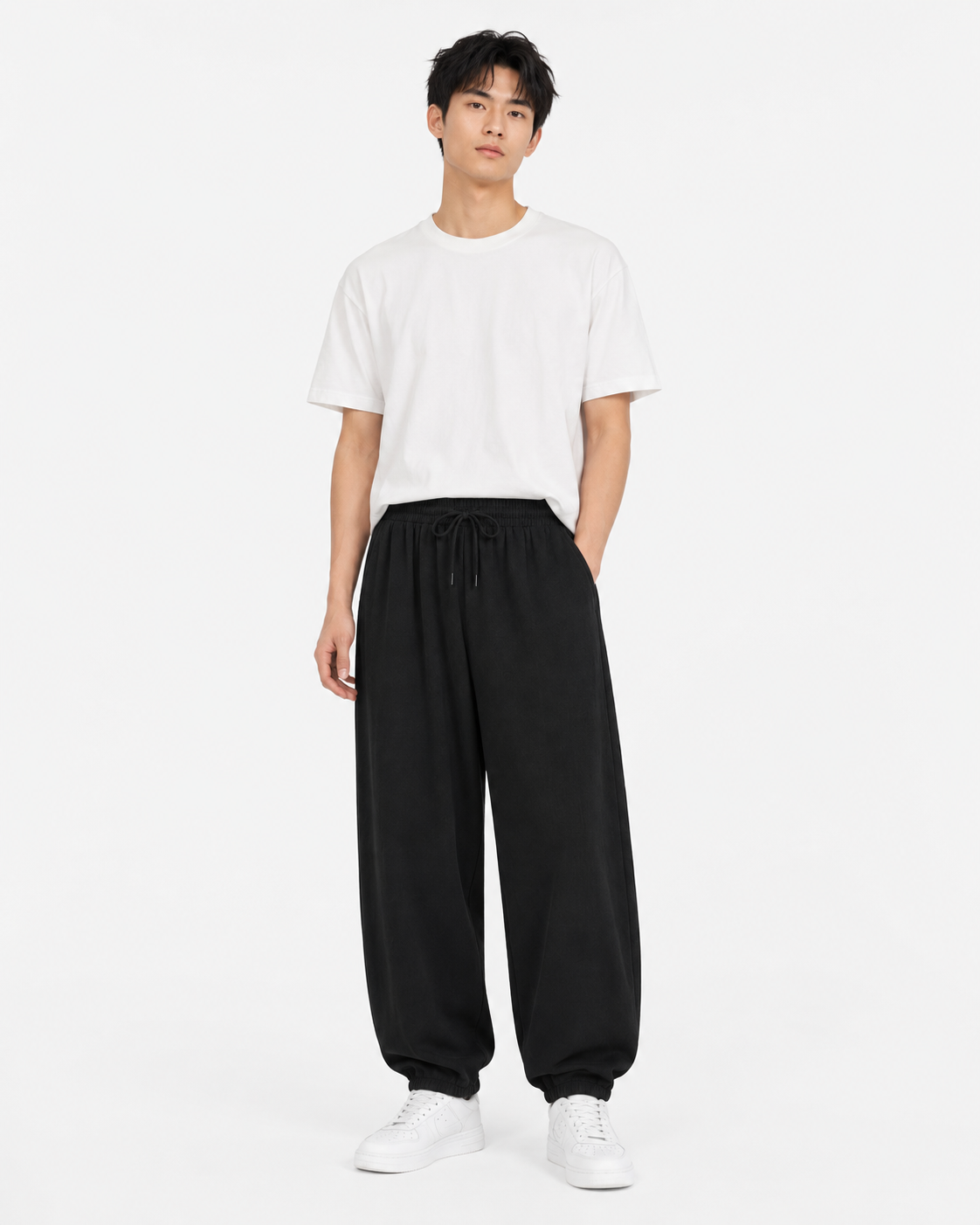 Black relaxed tapered drawstring pants worn by a male model on white background