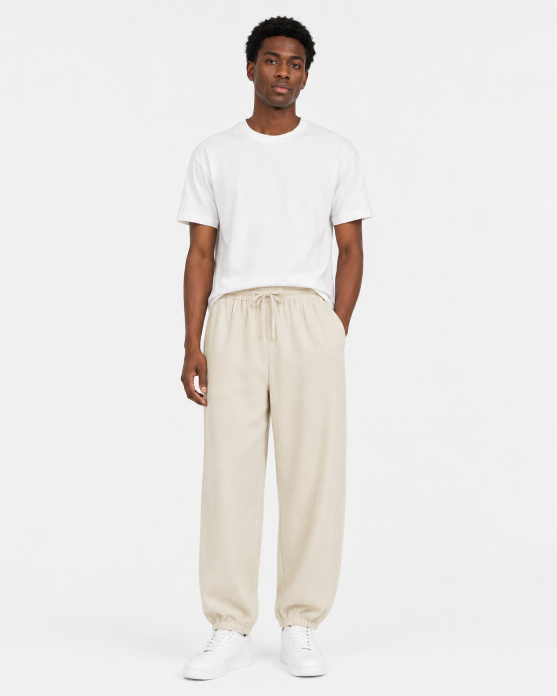 Khaki relaxed tapered drawstring pants worn by a Black male model on white background
