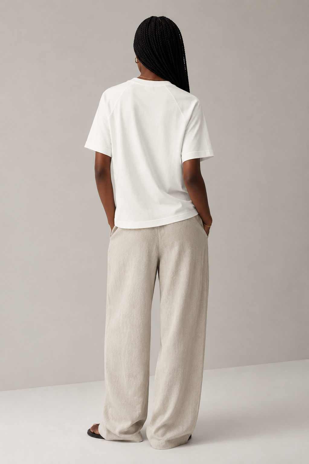 Professional female model wearing the Stitchwork Cotton Tee in beige white — back view